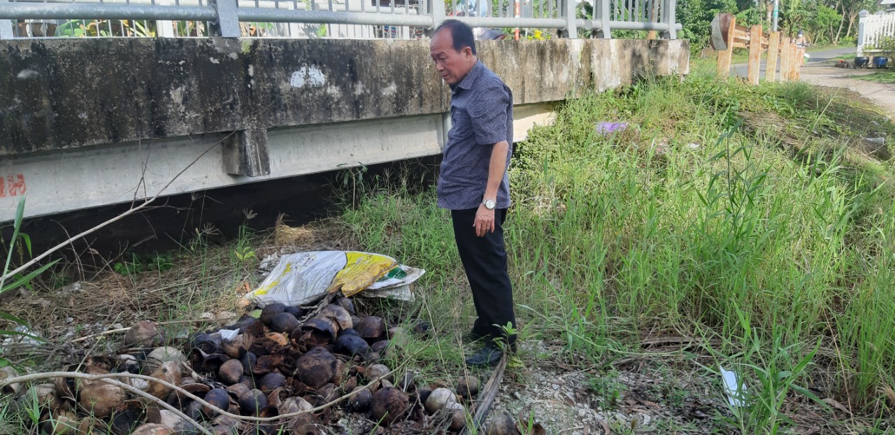 Đồng chí Huỳnh Văn Dũng - Giám đốc Trung tâm Y tế thị xã Giá Rai  nhặt từng vỏ dừa lật úp lại để không còn chứa nước mưa.